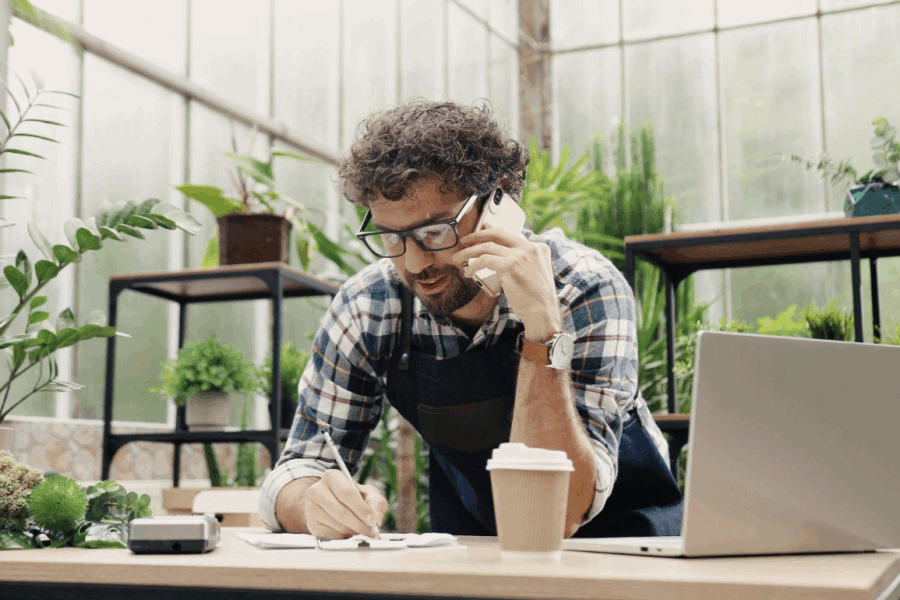 business man talking on the phone with plants behind him